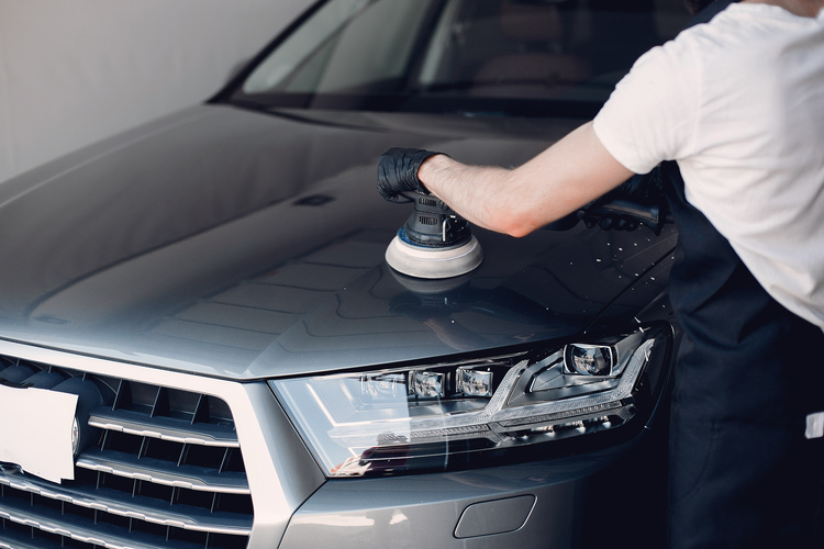 Man in a garage. Worker polish a car.